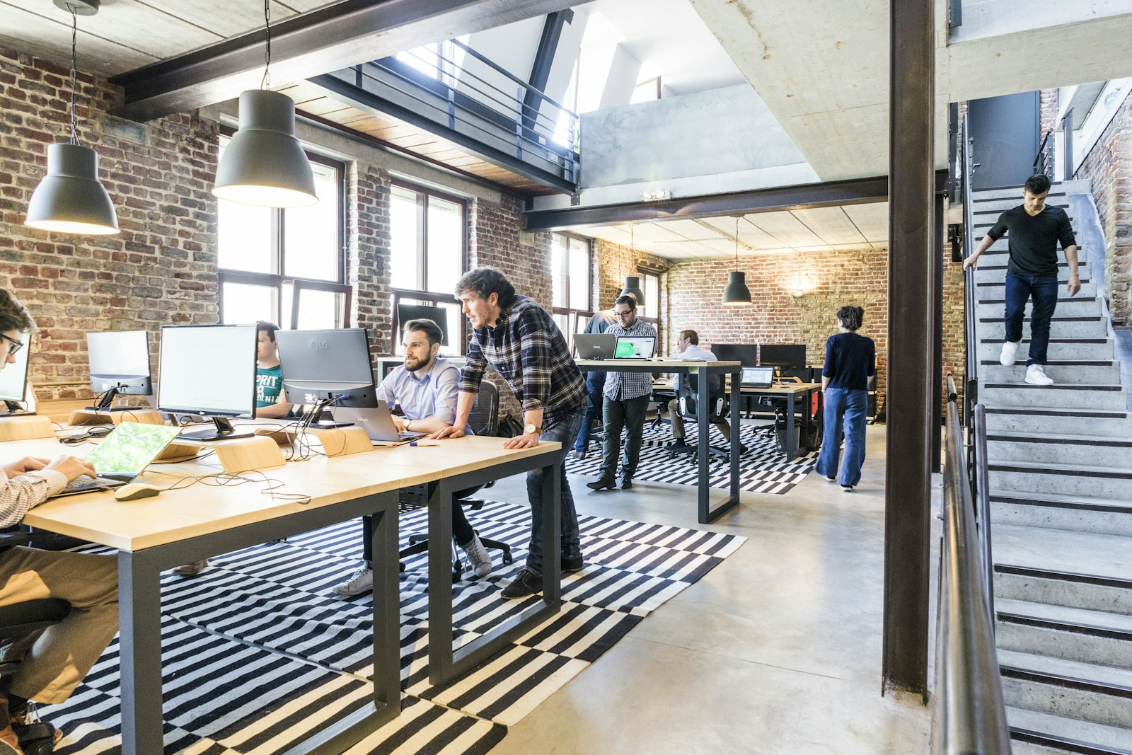 Open-plan brick-walled office with a team working across desks and monitors