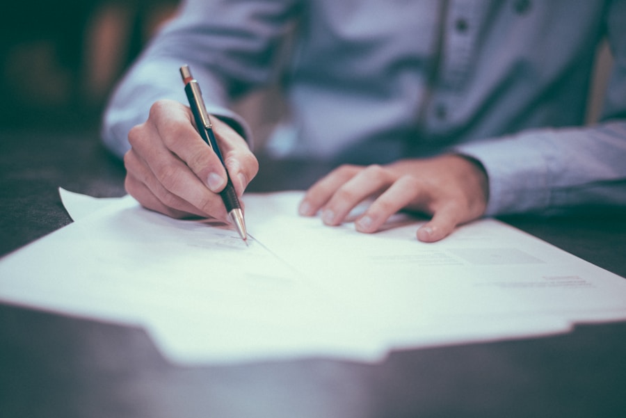 A person in a dress shirt signing legal documents with a pen