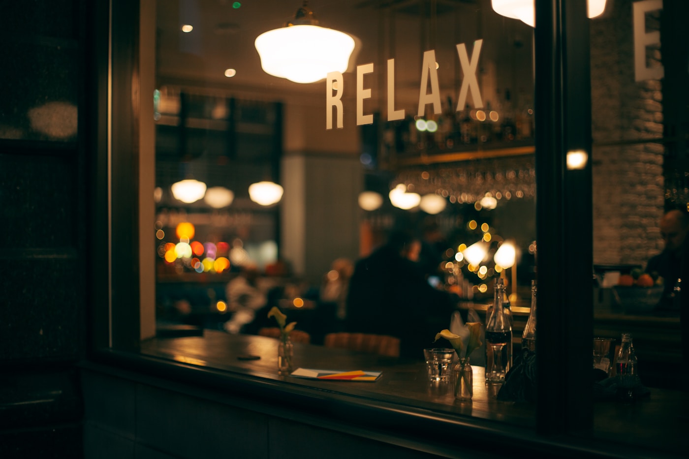 Restaurant bar seen through its street window at night, with RELAX lettering on the glass
